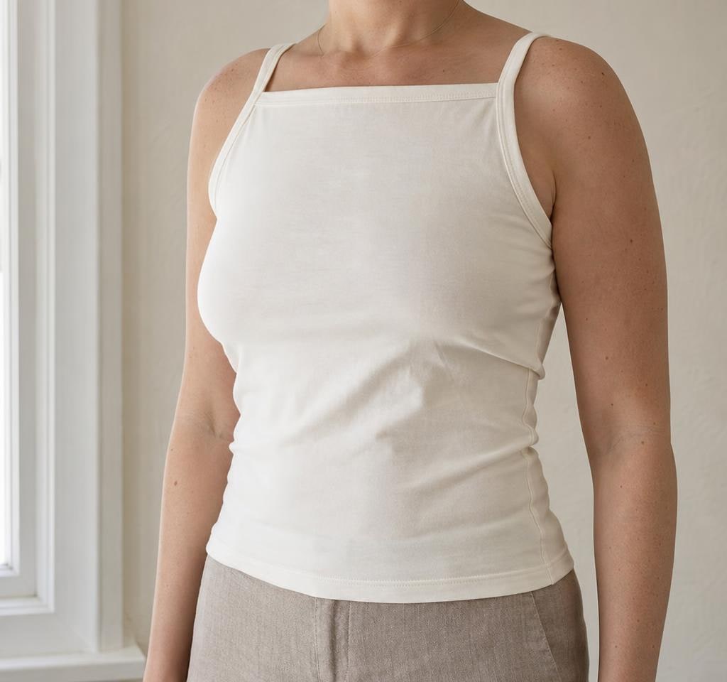 Adult woman in an ivory camisole and linen trousers in soft natural light